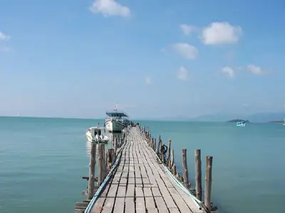 Sunset ferry crossing with motorcycles aboard, arriving at the paradise island of Koh Samui with coconut groves and waterfalls