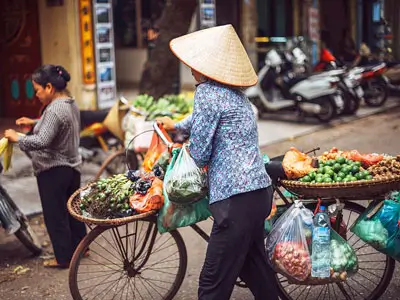 Rues vibrantes du Vieux Quartier de Hanoi avec le lac Hoan Kiem en arrière-plan, idéal pour un road trip en Royal Enfield au Vietnam.